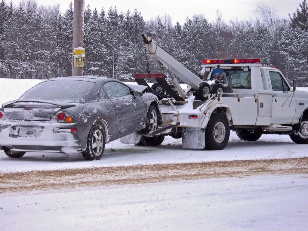 Tow Truck with a car being towed in snow